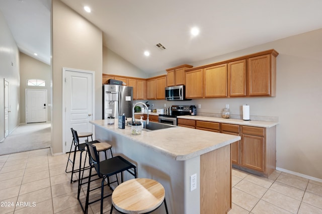 kitchen with high vaulted ceiling, stainless steel appliances, sink, a center island with sink, and light tile patterned floors