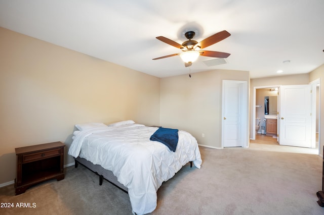 bedroom with ceiling fan, light colored carpet, and connected bathroom