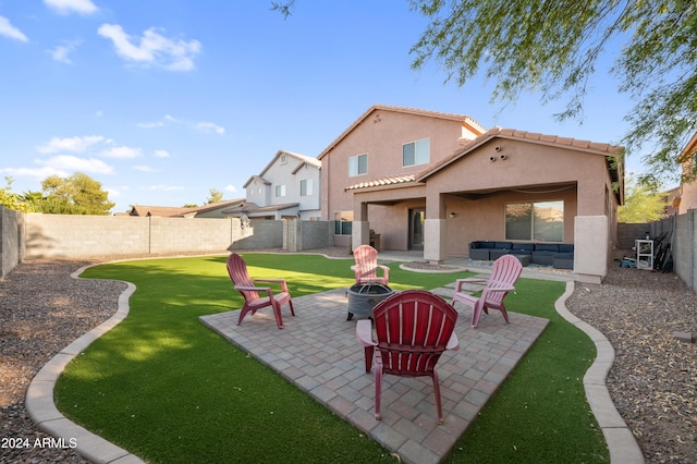 rear view of property with a lawn, a fire pit, and a patio area