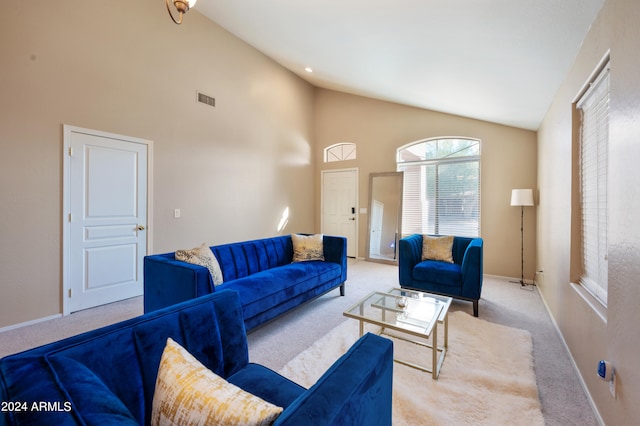 carpeted living room with high vaulted ceiling