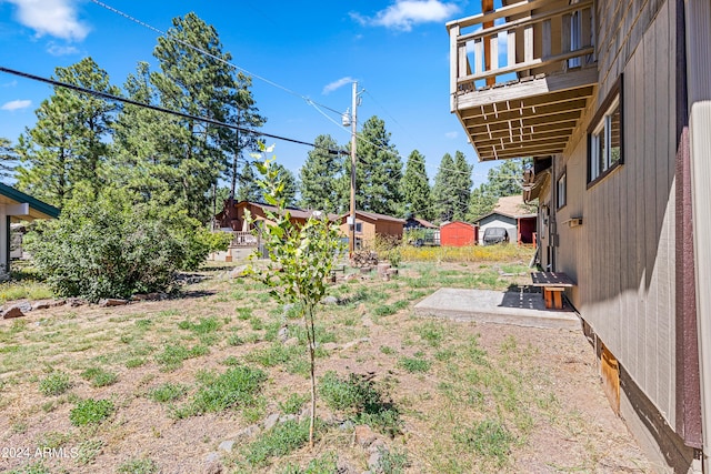 view of yard featuring a balcony and a shed