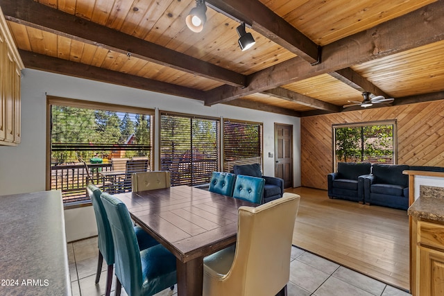 dining room with beamed ceiling, wood walls, ceiling fan, wood ceiling, and light hardwood / wood-style floors