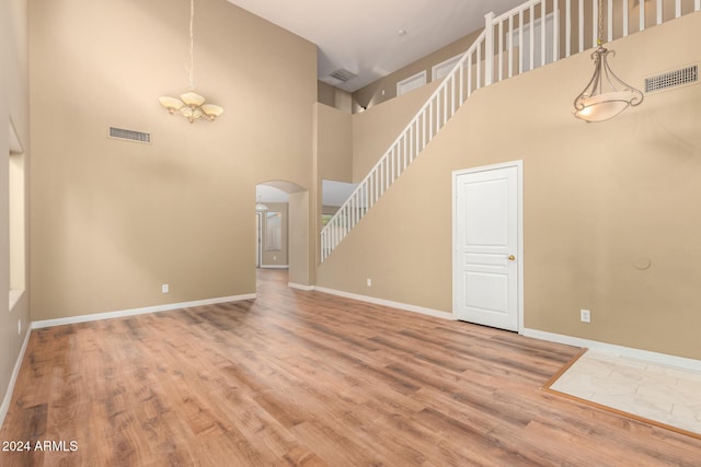 unfurnished living room with hardwood / wood-style flooring and a towering ceiling