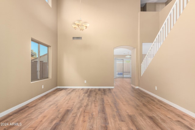 interior space with hardwood / wood-style floors, a towering ceiling, and a chandelier