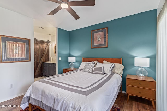 9450 E Becker Ln Unit 1046, Scottsdale, AZ 85260 - bedroom featuring a barn door, wood finished floors, baseboards, connected bathroom, and a ceiling fan