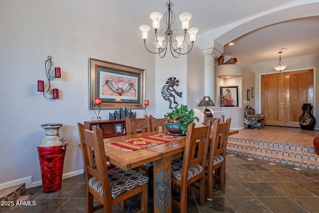 5336 E Gloria Ln, Cave Creek, AZ 85331 - dining room featuring arched walkways, baseboards, a chandelier, stone tile flooring, and ornate columns