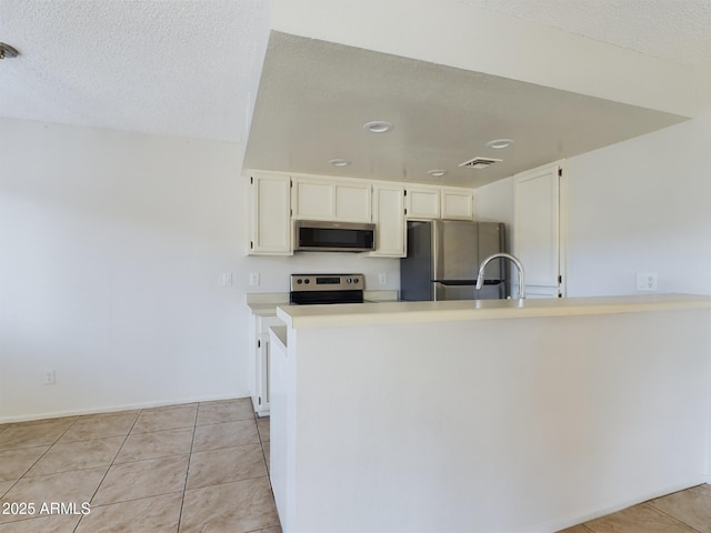 kitchen featuring a textured ceiling, white cabinets, stainless steel appliances, kitchen peninsula, and light tile patterned floors