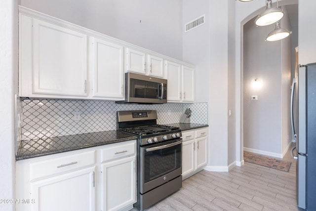 3055 N Red Mtn Unit 122, Mesa, AZ 85207 - kitchen featuring stainless steel appliances, white cabinetry, backsplash, baseboards, and dark stone countertops