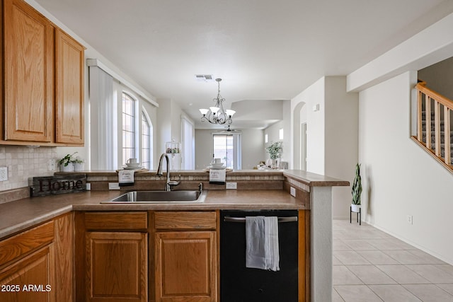 kitchen featuring a chandelier, dishwashing machine, a sink, a peninsula, and tasteful backsplash