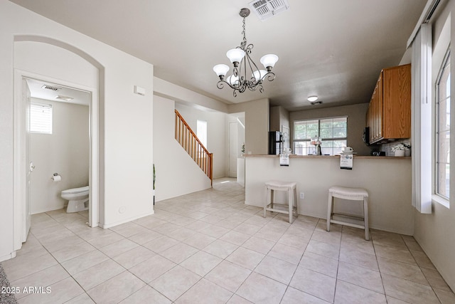 kitchen with brown cabinetry, visible vents, a wealth of natural light, and light tile patterned floors