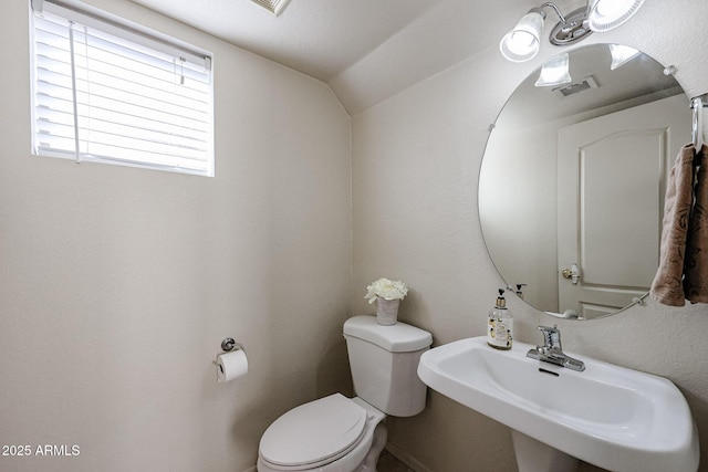 bathroom featuring vaulted ceiling, visible vents, a sink, and toilet