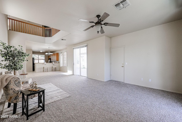 living room with carpet floors, visible vents, and ceiling fan with notable chandelier