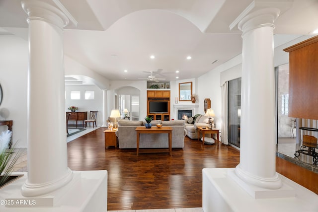 living room with decorative columns, dark hardwood / wood-style floors, a wealth of natural light, and ceiling fan