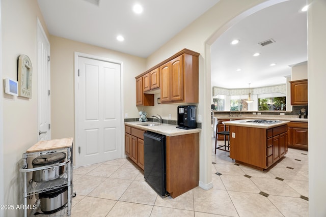 kitchen featuring light tile patterned floors, gas cooktop, dishwasher, a kitchen island, and decorative light fixtures