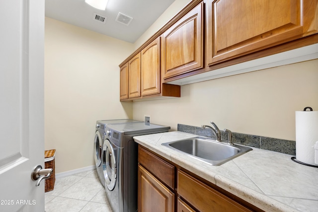 laundry area with cabinets, separate washer and dryer, sink, and light tile patterned floors