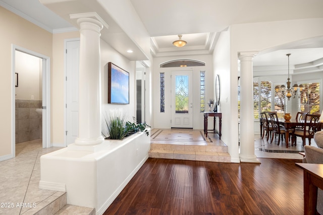 entrance foyer featuring ornate columns, crown molding, a healthy amount of sunlight, and light hardwood / wood-style floors