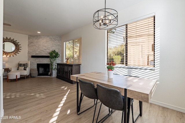 dining space featuring an inviting chandelier, a fireplace, and light hardwood / wood-style floors