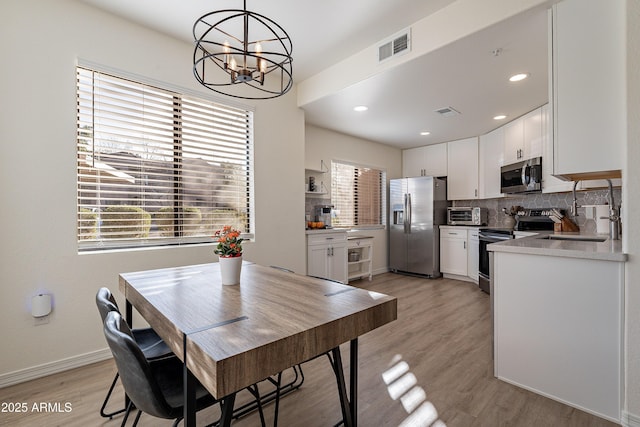 dining area featuring a notable chandelier, light hardwood / wood-style flooring, and sink