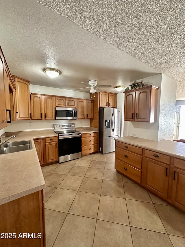 kitchen with sink, light tile patterned floors, ceiling fan, appliances with stainless steel finishes, and a textured ceiling