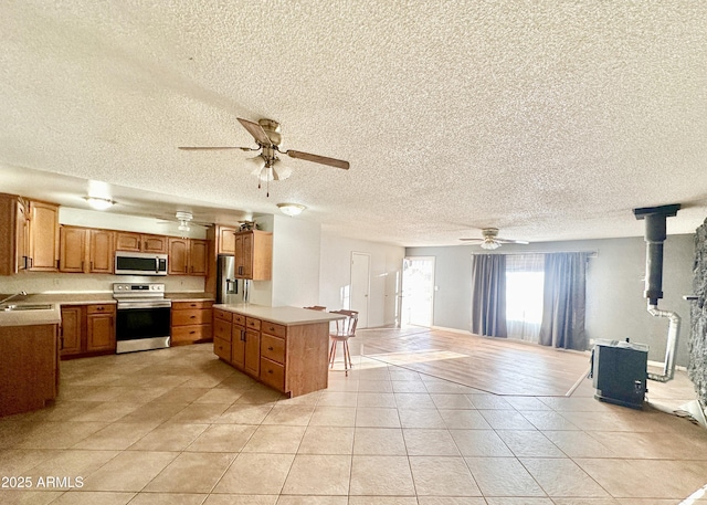 kitchen with light tile patterned flooring, sink, a wood stove, a kitchen breakfast bar, and stainless steel appliances