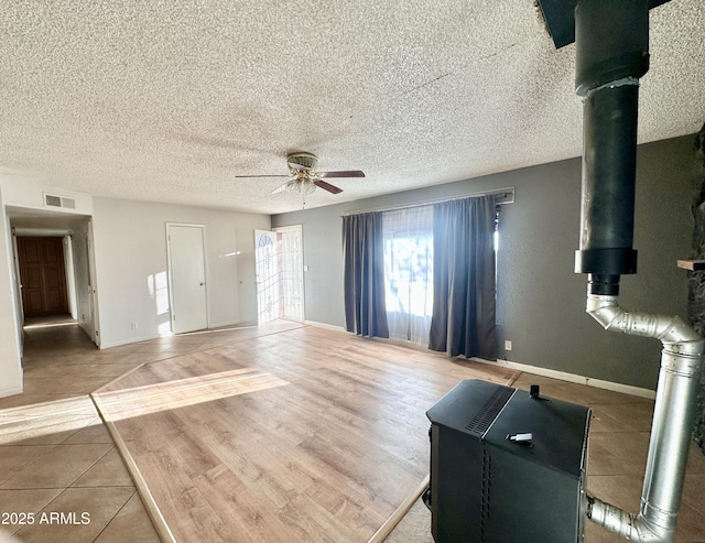 unfurnished living room featuring ceiling fan, a textured ceiling, wood finished floors, visible vents, and baseboards