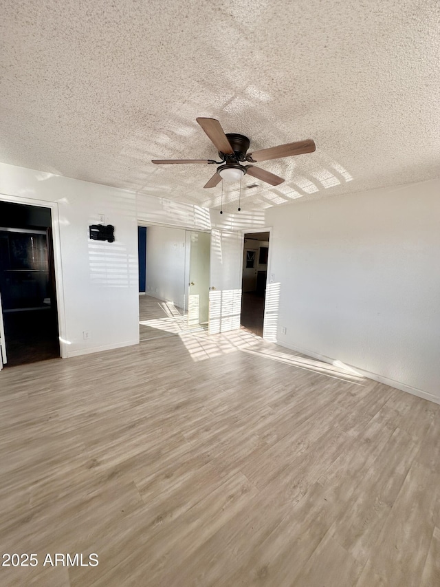 unfurnished room with ceiling fan, a textured ceiling, baseboards, and wood finished floors