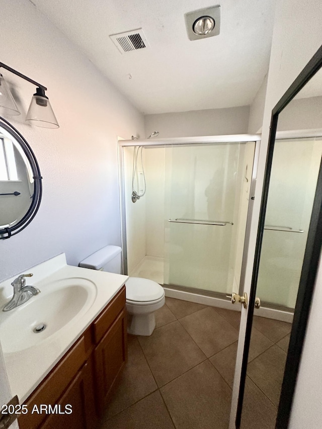 bathroom with visible vents, a shower stall, toilet, and vanity