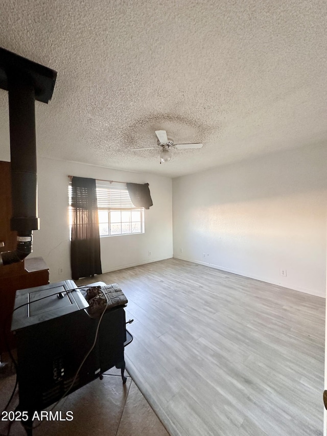 living room with ceiling fan, a textured ceiling, and light wood-type flooring