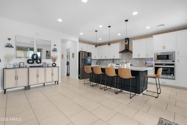 22501 E Indiana Ave, Queen Creek, AZ 85142 - kitchen with white cabinetry, a kitchen island with sink, decorative light fixtures, appliances with stainless steel finishes, and wall chimney exhaust hood