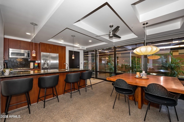 kitchen featuring pendant lighting, a raised ceiling, sink, ceiling fan, and stainless steel appliances