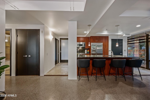 kitchen featuring pendant lighting, sink, a kitchen bar, kitchen peninsula, and stainless steel appliances