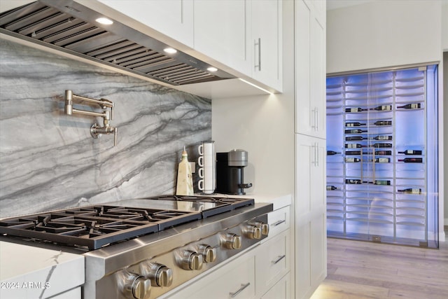 kitchen with white cabinets, tasteful backsplash, stainless steel gas stovetop, light hardwood / wood-style flooring, and premium range hood