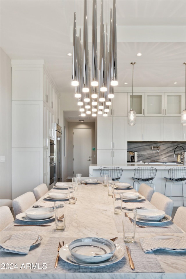 kitchen featuring light stone counters, decorative backsplash, pendant lighting, and white cabinets