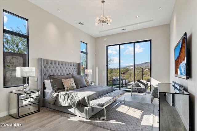 bedroom with light hardwood / wood-style flooring, access to exterior, and a notable chandelier