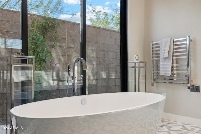 bathroom with tile patterned floors, sink, a tub to relax in, and radiator