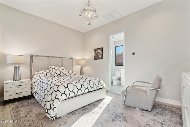 bedroom featuring ensuite bathroom, hardwood / wood-style flooring, and an inviting chandelier