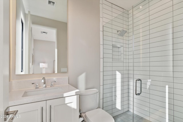 bathroom featuring vanity, toilet, and a shower with shower door