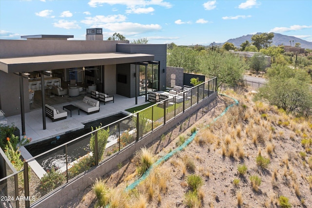 back of house with an outdoor living space, a mountain view, and a patio