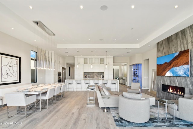 living room with a high end fireplace, sink, and light hardwood / wood-style flooring