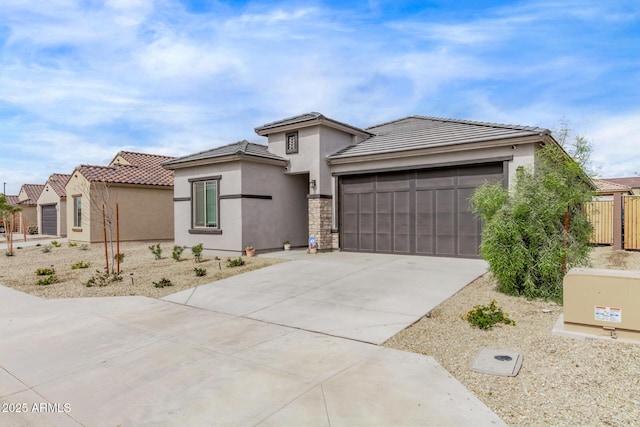 prairie-style house featuring fence, a tiled roof, concrete driveway, stucco siding, and an attached garage