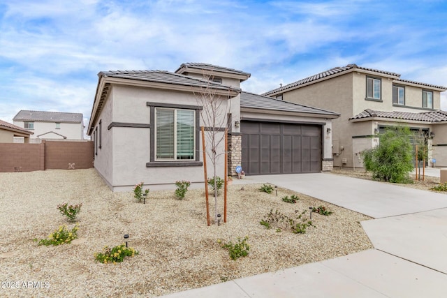 view of front of property with concrete driveway, fence, a garage, and stucco siding