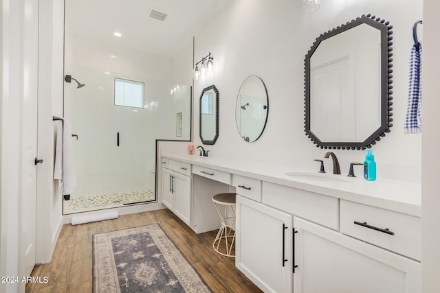 bathroom with hardwood / wood-style flooring, vanity, and a shower with shower door