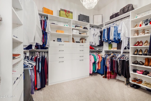 walk in closet featuring light carpet and an inviting chandelier