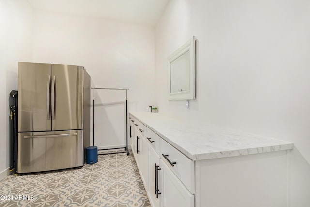 kitchen featuring stainless steel refrigerator, white cabinets, and light tile patterned flooring