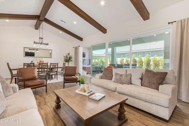 living room featuring a wealth of natural light, vaulted ceiling with beams, hardwood / wood-style floors, and an inviting chandelier