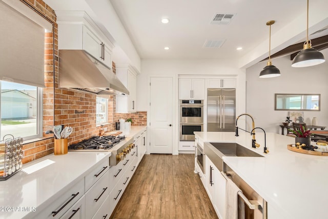 kitchen featuring appliances with stainless steel finishes, decorative light fixtures, sink, white cabinets, and backsplash