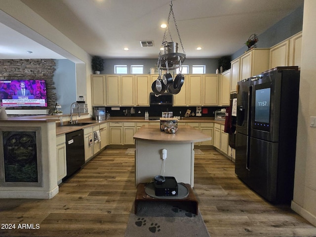 kitchen featuring sink, black appliances, hardwood / wood-style flooring, and a kitchen island