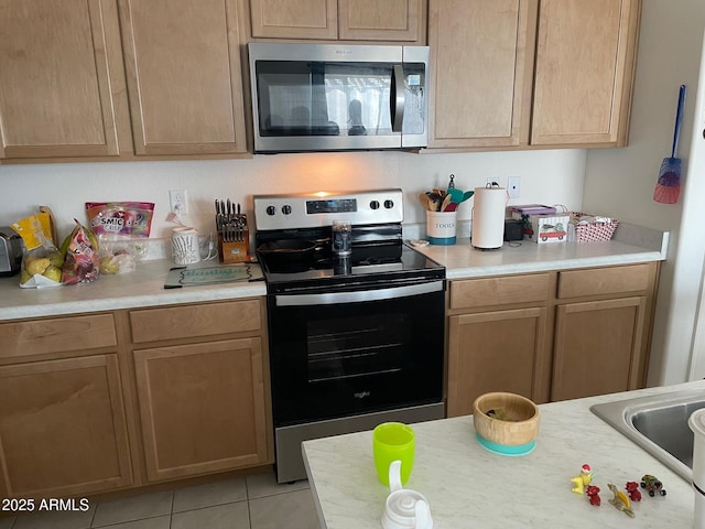 kitchen with stainless steel appliances, sink, and light tile patterned floors