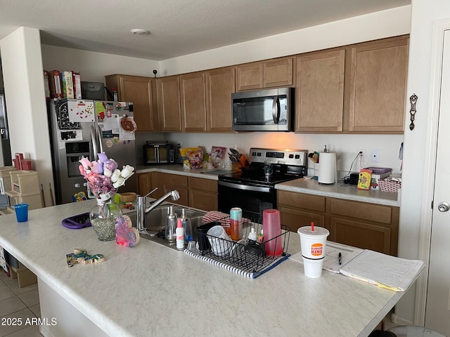 kitchen with appliances with stainless steel finishes, a center island with sink, and light tile patterned floors