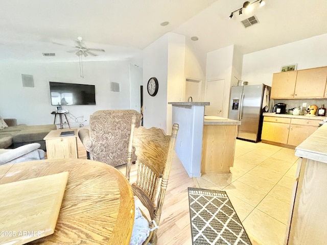 kitchen featuring stainless steel refrigerator with ice dispenser, light brown cabinets, a ceiling fan, open floor plan, and light countertops